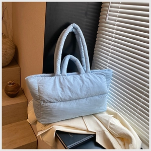 Quilted light blue down tote bag showing puffy texture and soft shoulder straps
