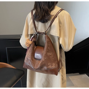 Detail of dark brown tote bag with bear charm and adjustable shoulder strap