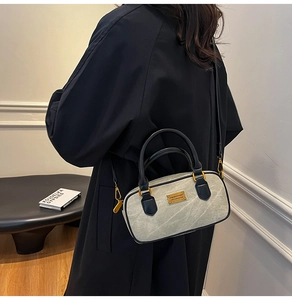 Detail view of marble texture Boston bag with black handles and gold metal accents