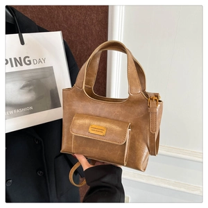 Détail d'un sac à main rétro marron en cuir PU avec poche avant et étiquette métal