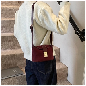 Detail of burgundy frosted leather crossbody bag featuring elegant gold square metal clasp