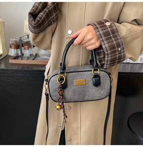 Detail of vintage grey boston bag with gold hardware and woven bell charm accessory