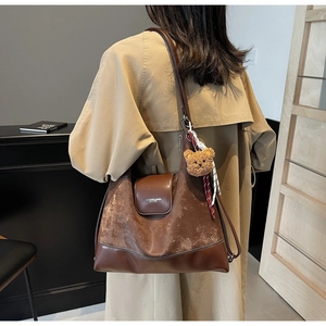 Detail of vintage brown tote bag with matte texture and cute plush bear accessory