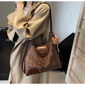 Close-up of brown leather tote bag with vintage matte texture and bear charm detail