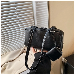 Detail of a black rectangular shoulder bag with slim straps and a matching coin purse
