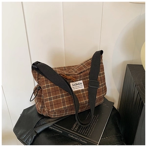 Detail of checkered canvas bag featuring brown plaid pattern and adjustable wide strap