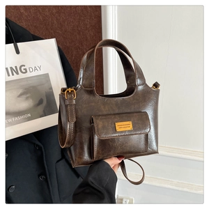 Détail d'un sac bandoulière vintage en cuir café avec plaque métal et poche avant