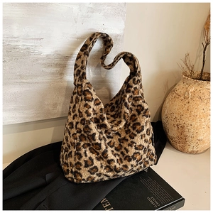 Détail d'un sac fourre-tout en peluche léopard posé sur un costume noir élégant