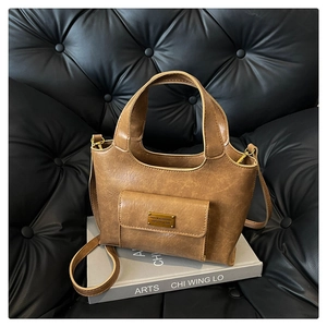 Détail d'un sac à main vintage marron avec plaque logo dorée et poche frontale