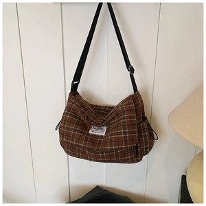 Detail view of brown checkered canvas texture and brand label on shoulder bag