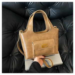 Gros plan du sac à main vintage marron avec poche frontale et emblème en métal doré