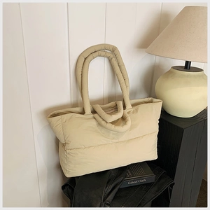 Detailed view of beige quilted tote bag with soft padded texture and round handles