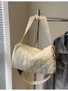 Off-white quilted canvas Boston bag with adjustable strap shown hanging with a denim jacket