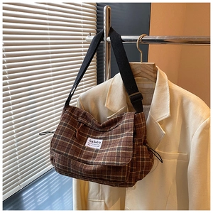 Detail of vintage brown plaid canvas shoulder bag with adjustable strap and brand patch