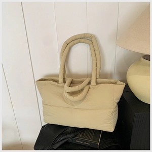 Detailed view of beige quilted puffer tote bag in a minimalist home interior setting
