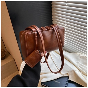 Detail view of a vintage brown leather pillow bag with dual zippers and a small coin pouch