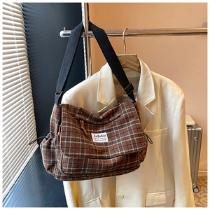 Close-up of brown plaid crossbody bag with JIASHUO brand tag on white suit jacket