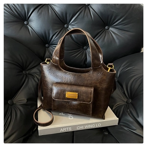 Gros plan du sac seau en cuir marron vintage avec ferrures dorées et poche latérale
