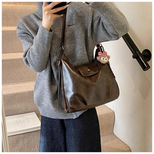 Dark brown vintage crossbody bag with half-round shape and plush charm on the strap