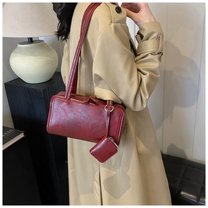 Macro detail of red leather underarm bag featuring a stylish mini pouch and metallic zip