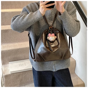 Detail of dark brown leather backpack with adjustable straps and plush charm on side