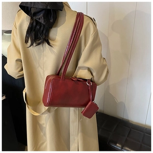 Detail of burgundy Boston bag on trench coat with a small detachable coin purse