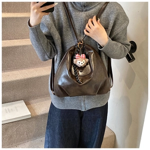 Brown soft leather backpack with geometric folds and plush bear charm shown in use
