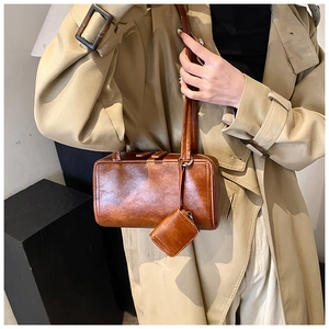 Detailed macro view of vintage brown leather cylinder bag with mini square coin purse charm