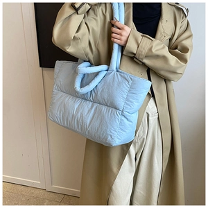 Detail of light blue quilted puffer tote bag shown on shoulder for daily commute style