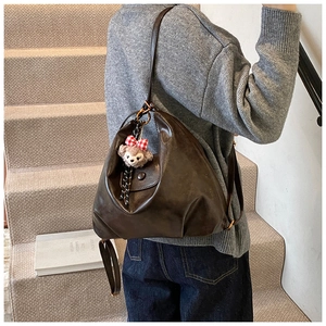 Detail of soft brown faux leather backpack with vintage pleated design and bear charm