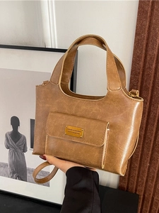 Sac à main en cuir PU marron avec poche avant et détails dorés dans une pièce épurée