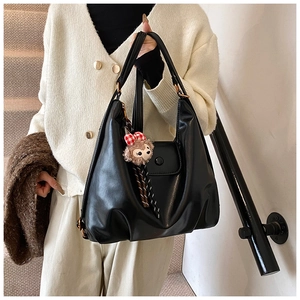 Detail of black large capacity hobo bag featuring a cute teddy bear charm on the handle