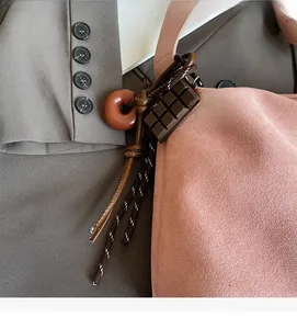 Detail of pink suede tote bag with chocolate and donut charms on a suit background
