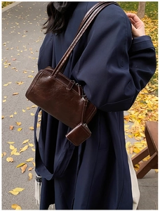 Outdoor shot of a vintage dark brown shoulder bag with a small matching pouch charm