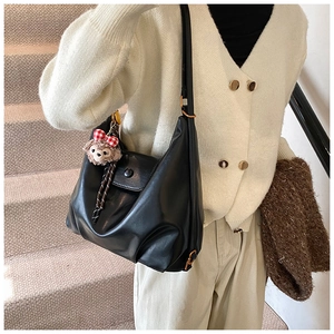 Detail of black soft leather hobo bag with ShellieMay plush charm and metal magnetic buckle