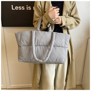 Macro detail of mid-grey quilted down tote bag with long padded handles for shoulder wear
