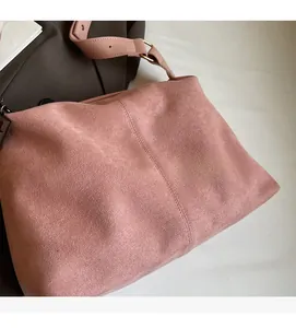 Close-up of pink suede shoulder bag showing soft matte texture and gold metal buckle