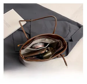 Vue intérieure du sac seau en similicuir marron montrant sa grande capacité et sa poche zippée