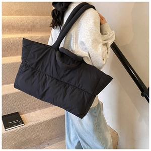 Macro detail of the black quilted puffer tote bag with soft padded nylon texture