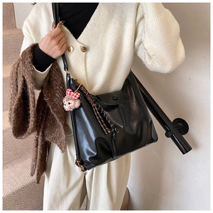 Detail of black faux leather tote bag with woven strap and magnetic buckle on the side