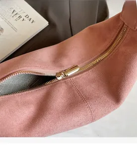Detailed macro shot of smooth gold-tone zipper on pink suede faux leather tote bag