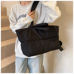 Detail of black puffer tote bag with quilted nylon fabric and wide padded shoulder strap