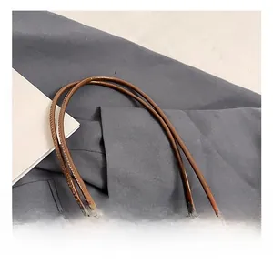Détail rapproché des poignées doubles confortables d'un sac seau en cuir marron ciré poli
