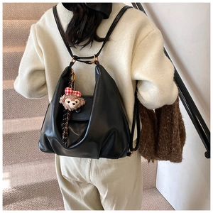 Detail of black leather backpack with gold buckles and a cute plush bear charm accessory