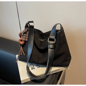 Detail of black suede hobo bag with wide leather strap and cute decorative charms