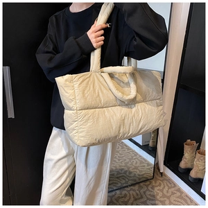 Chic quilted down tote bag in beige shown carried as a spacious shoulder bag by a model