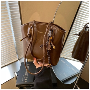 Détail du sac cabas en cuir marron foncé avec pendentif raquette de tennis