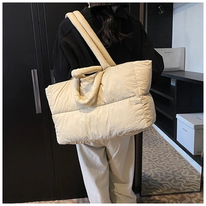 Quilted tote bag detail showing dual handles and textured beige nylon fabric on shoulder