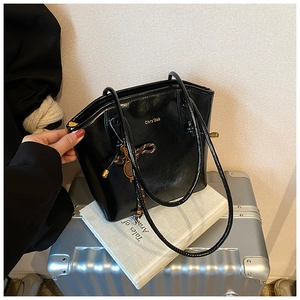 Gros plan sur un sac à bandoulière noir brillant avec breloque raquette de tennis dorée