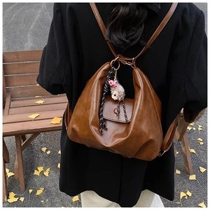 Brown soft leather backpack with cute sheep charm shown in an autumn park setting